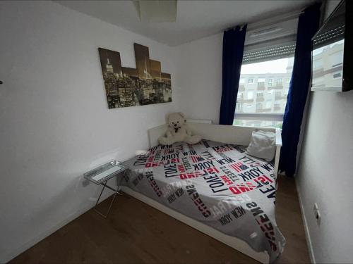 une chambre avec un ours en peluche assis sur un lit dans l'établissement LIMA HOUSE, à Goussainville