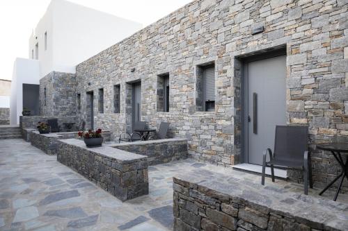 a stone building with a patio with chairs and a door at Aegeans Eye in Azolimnos