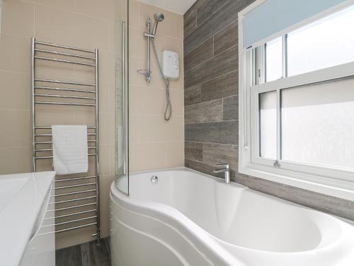 a white bath tub in a bathroom with a window at Rose Villa in Newlyn