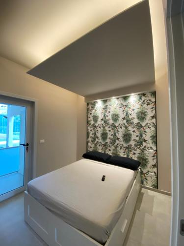 a bedroom with a white bed with a floral wall at Villa con piscina L’Approdo in Barletta