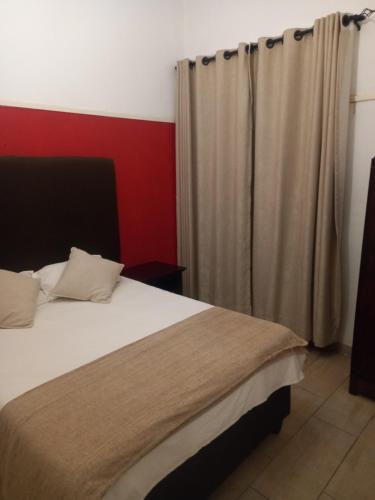 a bedroom with a large bed with a red wall at Choice Guesthouse and Backpackers in Bulawayo