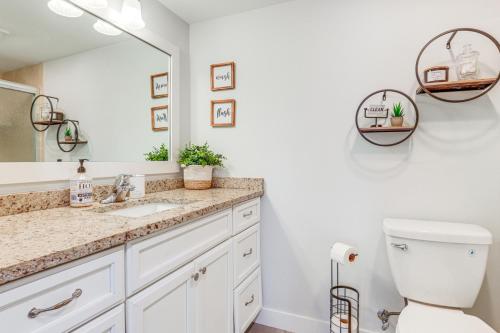 a bathroom with a sink and a toilet and a mirror at Fort Pierce Condo with Screened Porch Walk to Beach in Fort Pierce