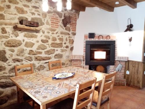 una sala da pranzo con tavolo e camino in pietra di La torna a Navarredonda de Gredos