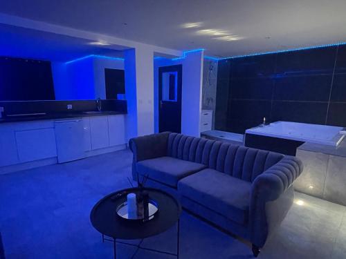 un salon avec un canapé et une cuisine avec des lumières bleues dans l'établissement Love Room avec Baignoire Balnéo Jacuzzi, à Saint-Étienne