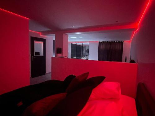 une chambre rouge avec un lit avec un éclairage rouge dans l'établissement Love Room avec Baignoire Balnéo Jacuzzi, à Saint-Étienne