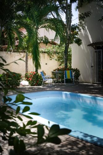a swimming pool with two chairs and a table and palm trees at Get Up Hostel in Natal