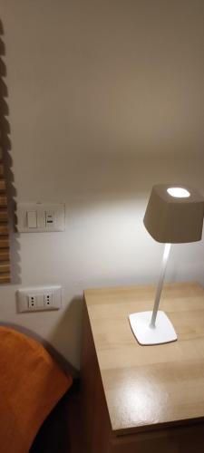 a lamp on a wooden table next to a bed at Margot's House Rho in Rho