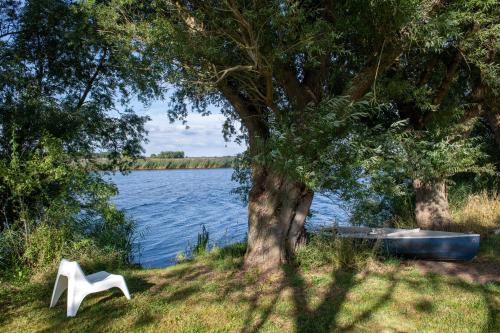 a white chair sitting next to a body of water at Reetdachhaus Eiderblick in Breiholz