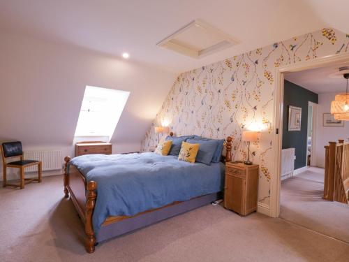 Schlafzimmer mit einem Bett mit blauer Decke in der Unterkunft Lime Tree Cottage, Blythburgh in Halesworth