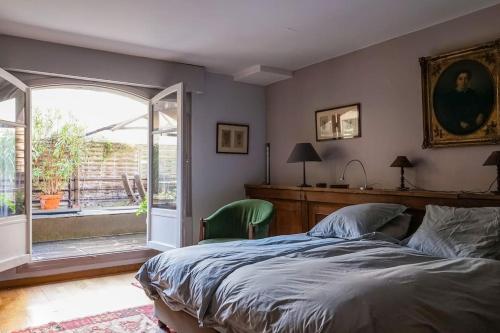 Loft avec terrasses en plein Paris في باريس: غرفة نوم بسرير ونافذة كبيرة