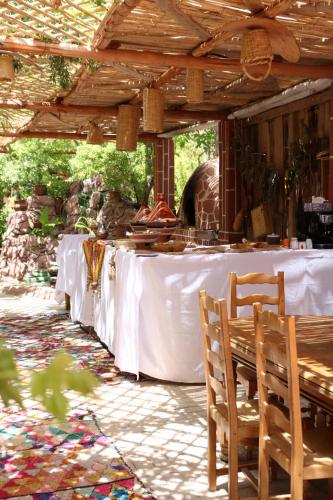 una mesa con un mantel blanco y sillas bajo una pérgola en Ecolodge Aroma Dades en El Hart