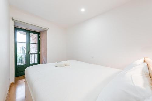 a white bed in a room with a window at GuestReady - Green Bay Garden in Porto