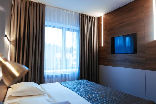 ein Schlafzimmer mit einem Bett und einem TV an der Wand in der Unterkunft DUO Futuro Hotel Bishkek in Bischkek