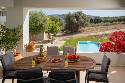 a wooden table with fruit on a patio with a pool at Luisa Holiday Home in Ádhele