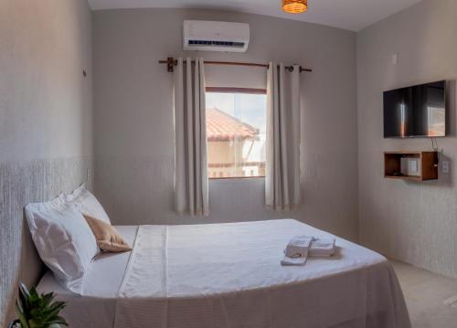 a bedroom with a white bed with a window at Pousada Rota do Kite Preá in Prea