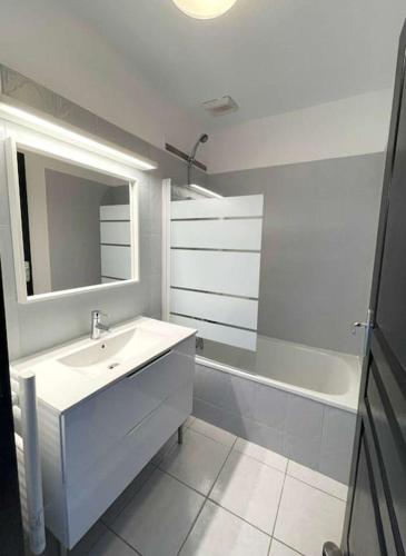 une salle de bain avec un lavabo, un miroir et une baignoire dans l'établissement BARCARESA-Villa cosy en bord de mer, idéalement située, au Barcarès