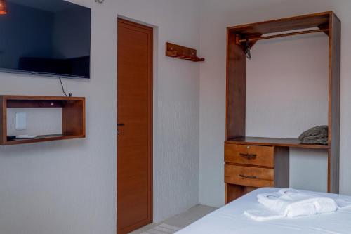 a bedroom with a bed and a dresser and a television at Pousada Rota do Kite Preá in Prea