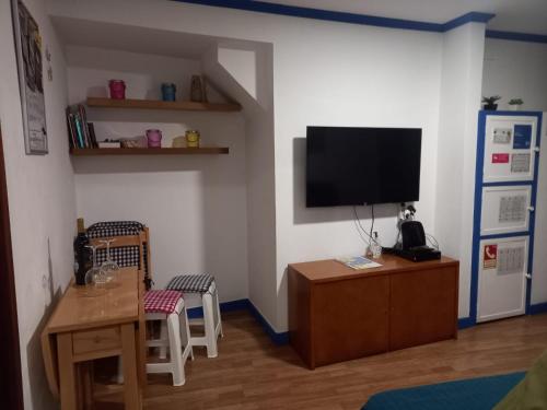 een woonkamer met een televisie en een tafel en stoelen bij Casa da Mariquinhas in Lissabon