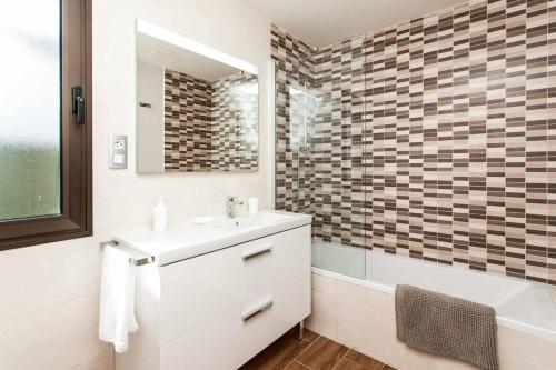 een badkamer met een wastafel, een bad en een spiegel bij Villa Diamante in Caleta De Fuste