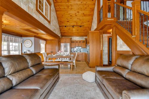a living room with brown leather couches and a staircase at Waterfront Romulus Getaway with Private Dock! in Romulus