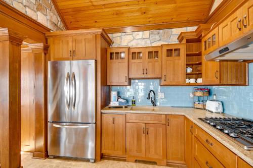a kitchen with wooden cabinets and a stainless steel refrigerator at Waterfront Romulus Getaway with Private Dock! in Romulus