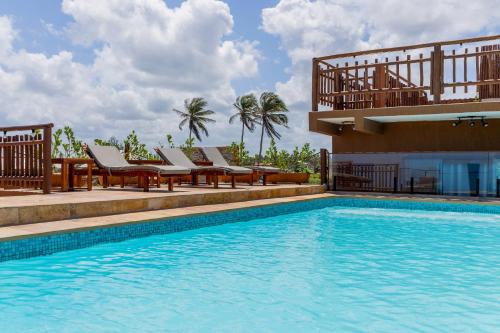 a swimming pool with chairs and a building at Pousada Rota do Kite Preá in Prea