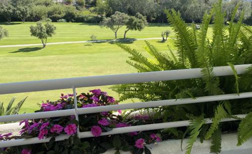 un balcón con flores y un campo verde en Duplex vistas al golf Guadalmina Marbella, en Marbella