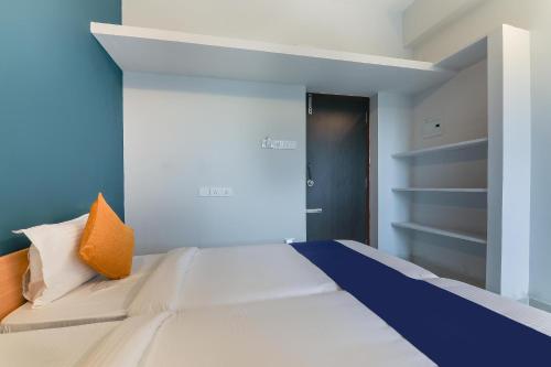 a bedroom with a white bed with an orange pillow at Hotel O Maraimalai Nagar in Singapperumālkovil
