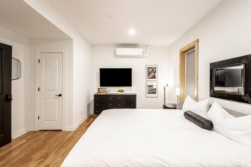 a white bedroom with a large bed and a flat screen tv at Historic DTWN Studio, Walk to Bathhouses, Shops, Room # 103 in Hot Springs