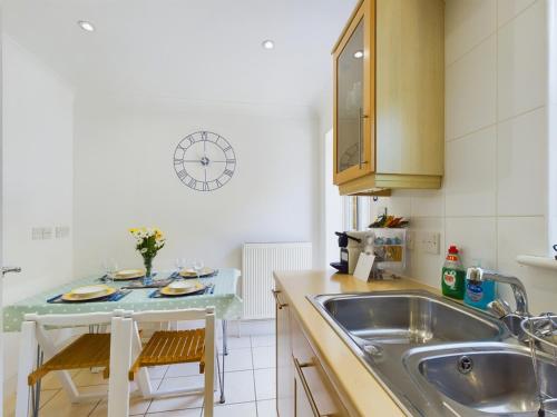 a kitchen with a sink and a table with chairs at 12A Solent Landing direct beach access in Bembridge