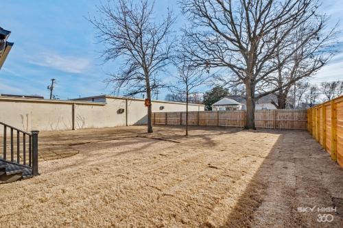 a dirt yard with a fence and two trees at The Price House in Springdale