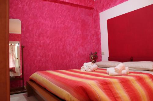 a bedroom with pink walls and a bed with towels at Casa Arcobaleno on Via Francigena in Gambassi Terme