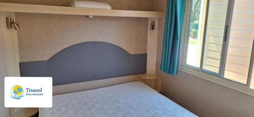 a bedroom with a bed with a blue headboard and a window at Comfortable campsite-chalet G8 Tuscany near sea in Viareggio