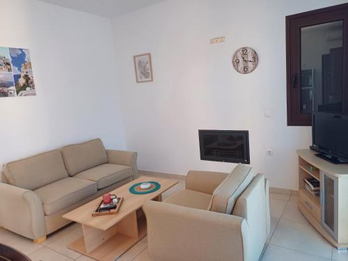 ein Wohnzimmer mit einem Sofa, einem Tisch und einem TV in der Unterkunft Angelica-Sea & Mountain View in Georgioupoli