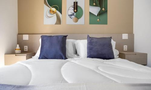 a bedroom with a large bed with blue pillows at Tabas - Pivô Match Jardins - Cravinhos in Sao Paulo