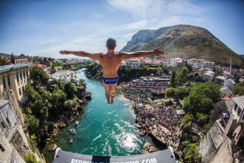 a man jumping into a river with his arms outstretched at Villa Deny Mostar - with free parking in Mostar