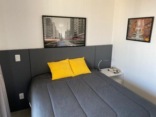 una camera con un letto con due cuscini gialli di Studio Quadra da Paulista a San Paolo