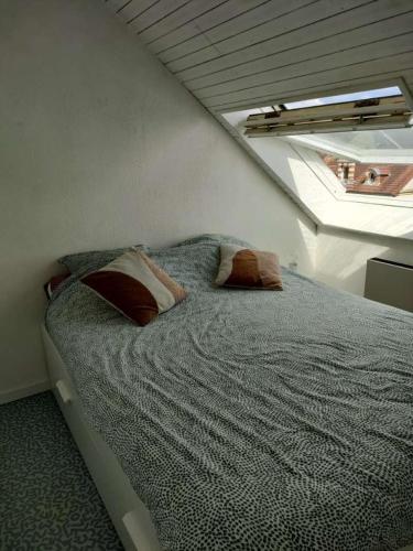 une chambre avec un lit avec des oreillers dessus dans l'établissement Appartement proche plage, à Ouistreham