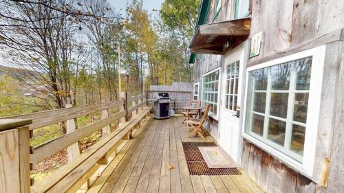 a wooden deck with a grill on a house at Pond View Cabin Brought to you by GetAway Vacations in Chittenden