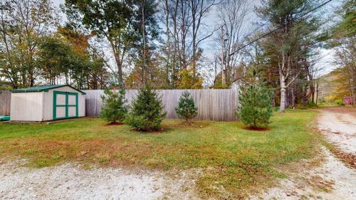 a backyard with a fence and trees and a shed at Pond View Cabin Brought to you by GetAway Vacations in Chittenden