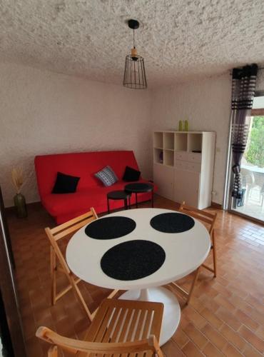 - un salon avec une table, des chaises et un canapé rouge dans l'établissement Appartement T1 cabine proche plage, à Lumio