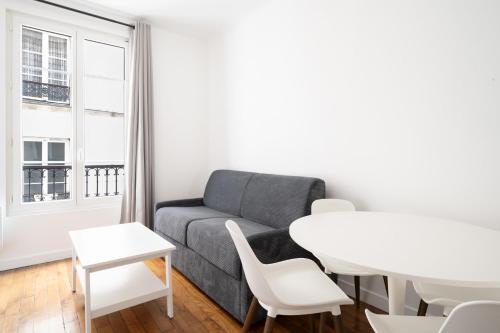 un salon avec un canapé et une table dans l'établissement Appartement Paris Blanche - Welkeys, à Paris