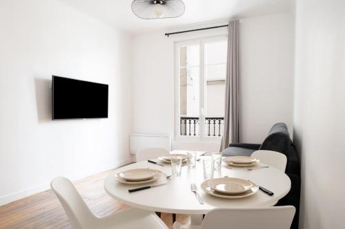 une salle à manger blanche avec une table et des chaises blanches dans l'établissement Appartement Paris Blanche - Welkeys, à Paris