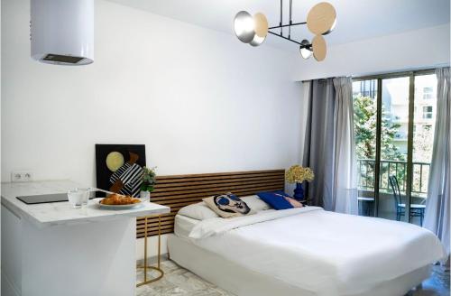 a white bedroom with a bed and a table at Majestic Apartment in Cannes