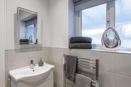 łazienka z umywalką, lustrem i oknem w obiekcie Cenarth w mieście Benllech