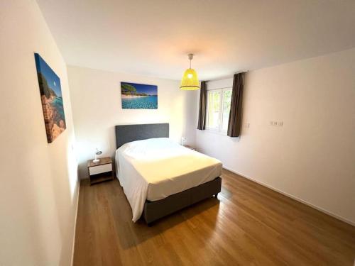- une chambre avec un lit blanc et du parquet dans l'établissement Location T2 premium 44 m2 Cala rossa à 800 m de la plage, à Lecci