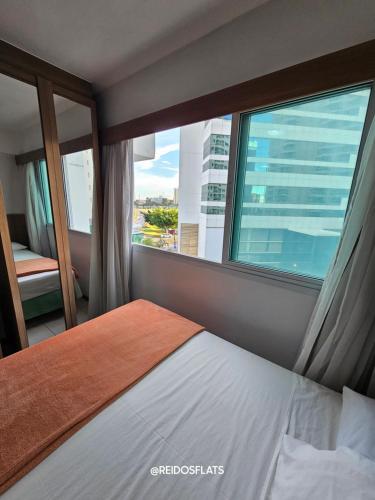 a bedroom with a bed and a large window at Flat Saint Moritz Express By Rei dos Flats in Brasilia