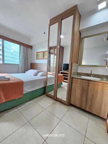 a bedroom with a bed and a mirror and a sink at Flat Saint Moritz Express By Rei dos Flats in Brasilia