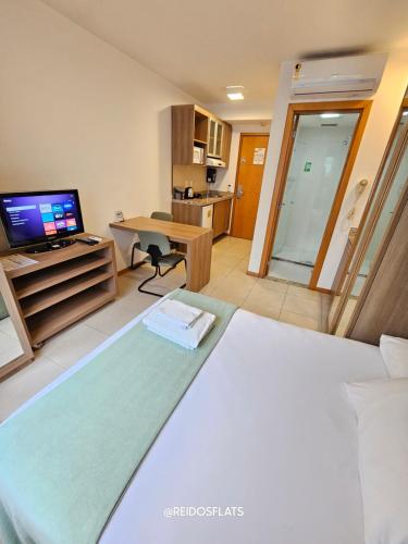 a bedroom with a bed and a desk with a television at Flat Saint Moritz Express By Rei dos Flats in Brasilia