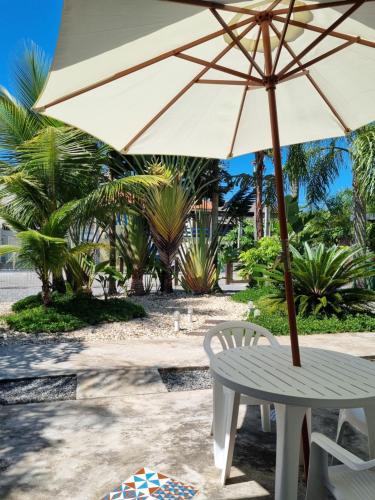 Canto das Ondas Apart Studios في ساو فرانسيسكو دو سول: طاولة وكرسي مع مظلة على الشاطئ